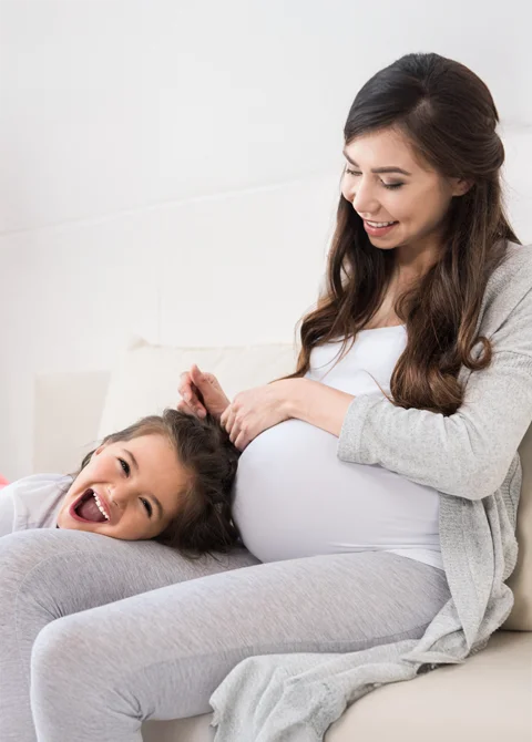 A pregnant mother laughing with her daughter